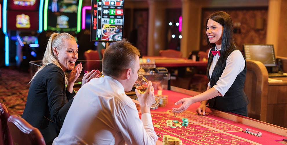 Table Games dealer smiling at man and woman | Learn about Careers at Two Kings Casino