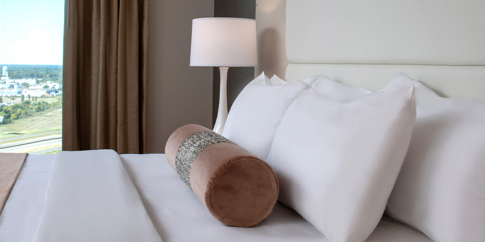 Image of hotel bed with pillows and blanket